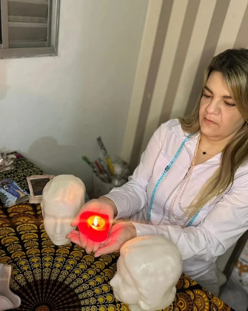 Vela acesa entre duas cabeças de cristal sobre a mesa de trabalho espiritual